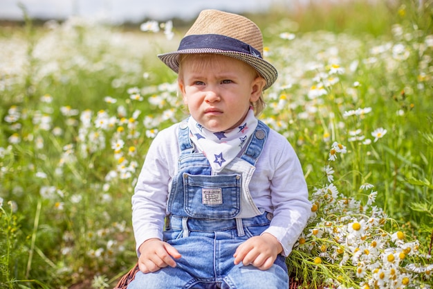 Retrato de adorable bebé con flores en campo de manzanilla