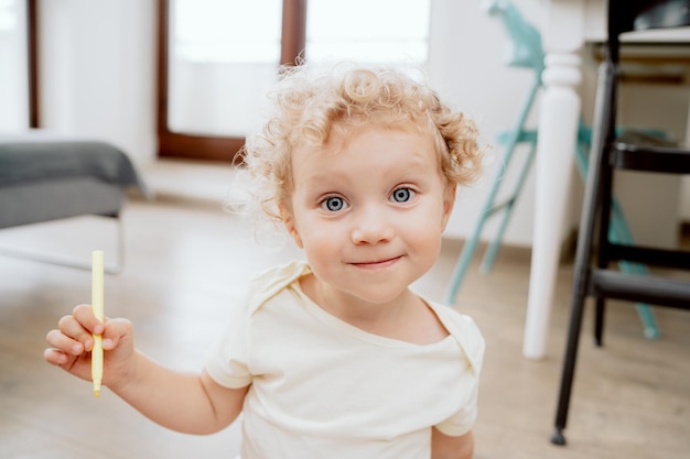 Retrato de una adorable y dulce niña en edad preescolar sentada en un suelo de madera en su salón