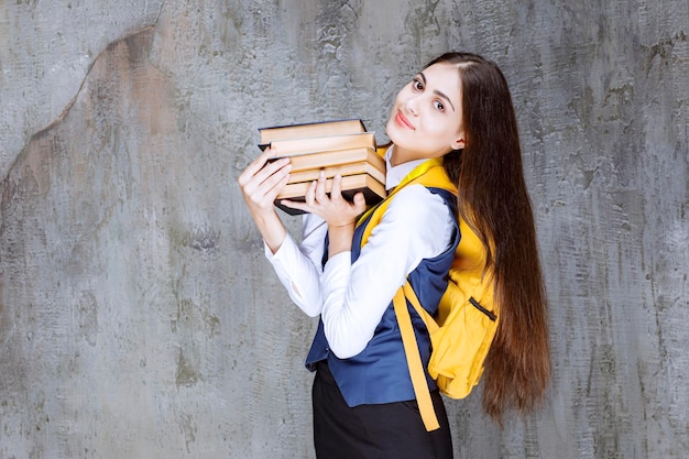 Retrato de adorable estudiante con mochila sosteniendo libros. foto de alta calidad