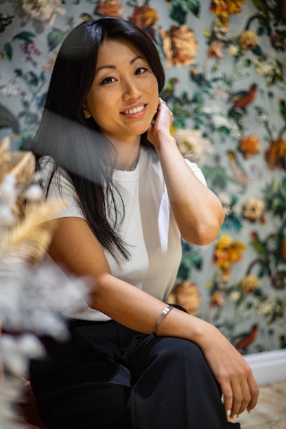 Retrato adorable mujer joven asiática morena sonriente posando en el interior de una casa de lujo