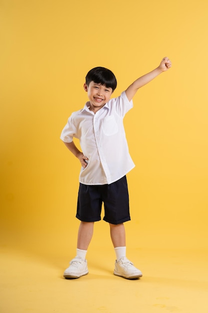 Retrato de un adorable niño asiático posando sobre un fondo amarillo