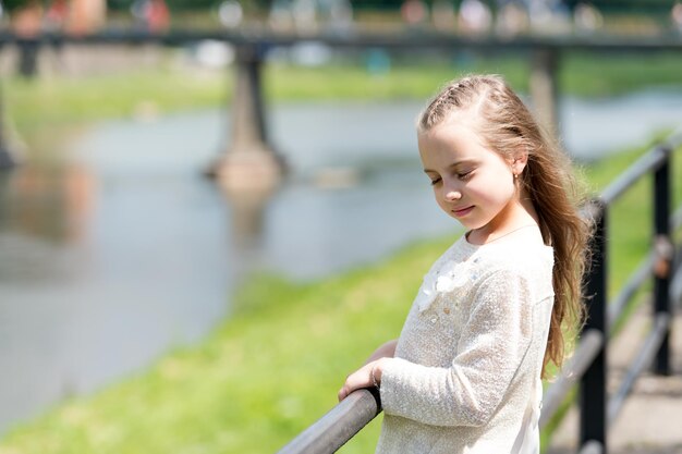 Retrato de una adorable princesa linda y feliz con el pelo largo y rubio rizado en el día soleado de verano