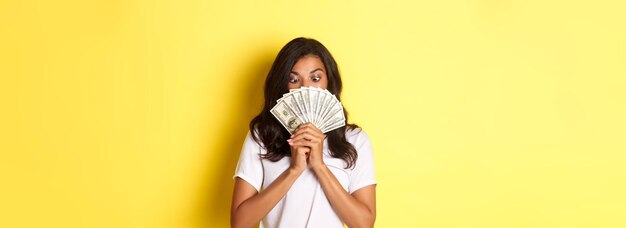 Foto retrato de la afortunada niña afroamericana ganando un premio en efectivo con efectivo y mirando asombrado de pie