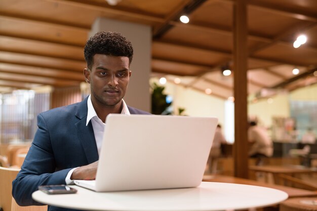 Retrato, de, africano, hombre de negocios, utilizar, computadora de computadora portátil, en, cafetería, tiro horizontal