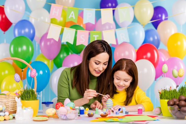 Retrato de agradable atractivo encantador creativo tierno alegre alegre niñas disfrutando de pintar huevos mamá mamá enseñando pequeña hermanita redhair