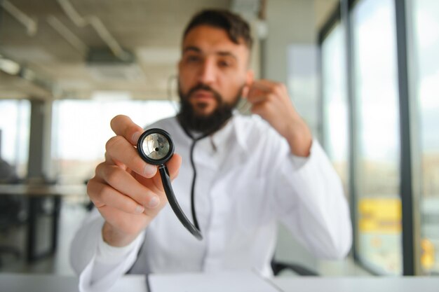 Foto retrato de un agradable joven médico árabe con bata blanca