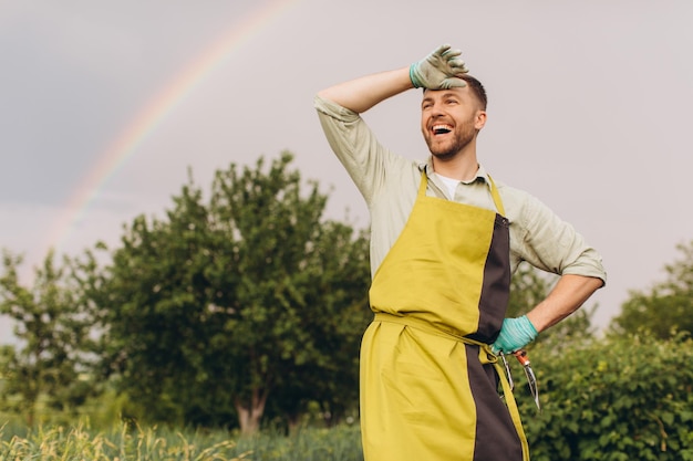 Retrato de un agricultor sonriendo sobre un fondo de arco iris en el jardín