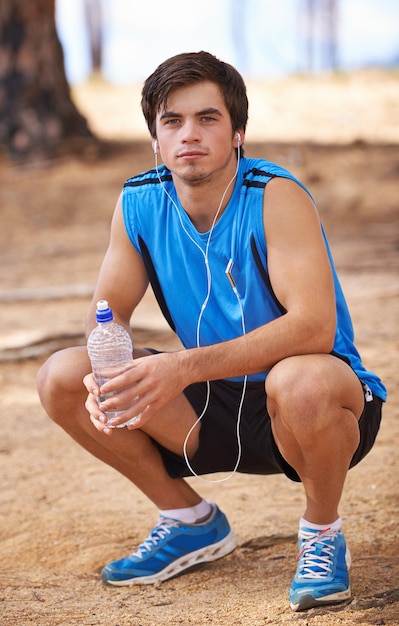 Retrato de agua o corredor en descanso con auriculares en ejercicio al aire libre o entrenamiento de fitness para podcast Hombre listo o atleta masculino escuchando una lista de reproducción para transmitir música de radio o entrenamiento deportivo