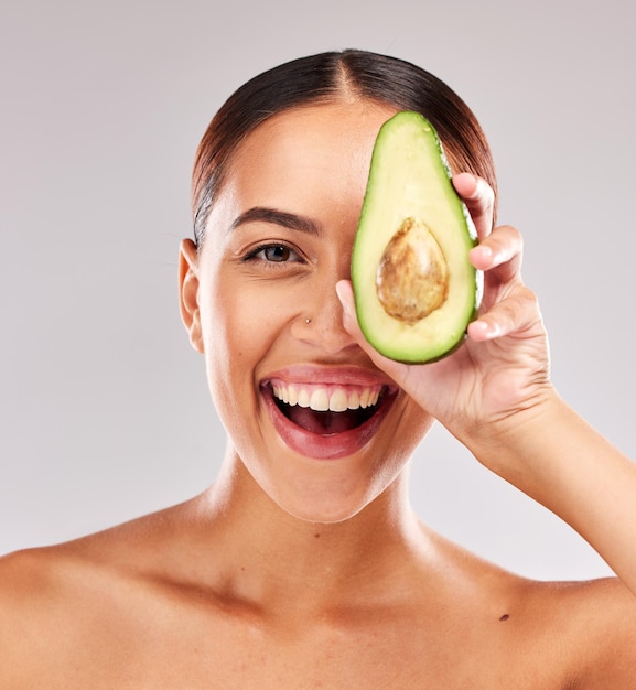 Retrato de aguacate y mujer con cuidado de la piel natural para el bienestar, la belleza y la nutrición sobre un fondo de estudio gris Salud alimentaria y modelo emocionado con una dieta saludable para el cuerpo y el estilo de vida