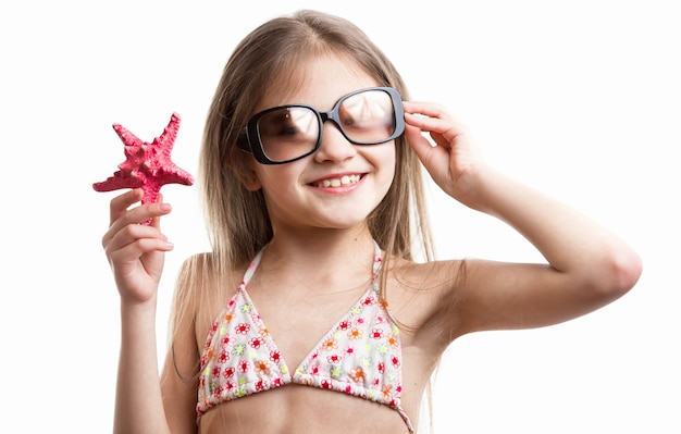 Retrato aislado de niña morena sonriente posando con estrella de mar roja