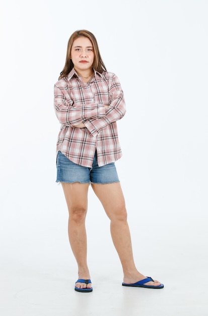 Retrato aislado recorte de estudio de cuerpo completo disparó asiático alegre modelo femenino feliz en casual camisa de manga larga a cuadros pantalones cortos jeans y zapatillas de pie de brazos cruzados sonriendo posando sobre fondo blanco