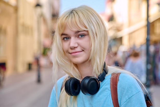 Retrato al aire libre de una chica feliz rubia de 17 años mirando a la cámara