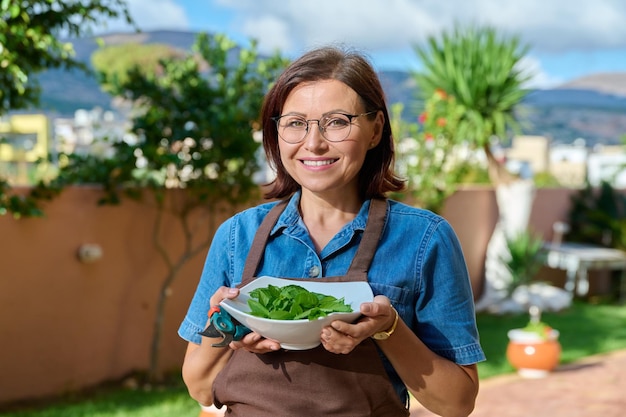 Retrato al aire libre de una cocinera sonriente en un delantal con un plato de menta fresca