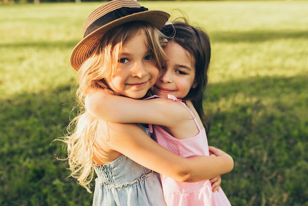 Retrato al aire libre de dos niños adorables que comparten amor y amistad Dos niñas jugando en el parque Dos hermanas divirtiéndose con la luz del sol y el fondo de la naturaleza Concepto de infancia y amistad