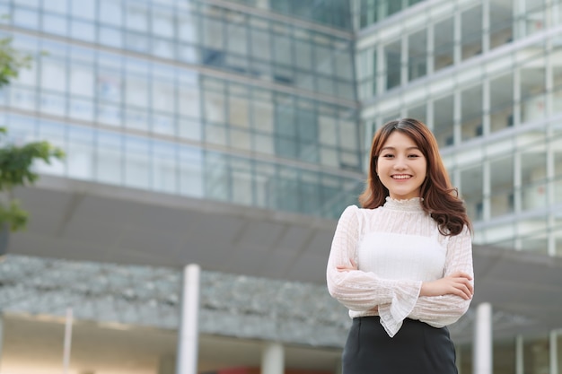 Retrato al aire libre de la empresaria madura en las calles de la ciudad, confiada mujer sonriente con los brazos cruzados