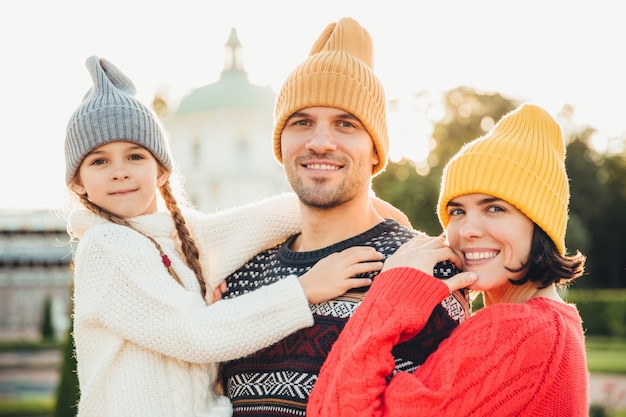 Retrato al aire libre de una familia amigable parada cerca uno del otro, sonrisas