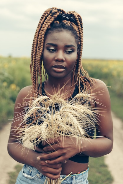 Retrato al aire libre de hermosa feliz mestiza niña afroamericana adolescente mujer joven en un campo de flores amarillas al atardecer sol de noche dorada