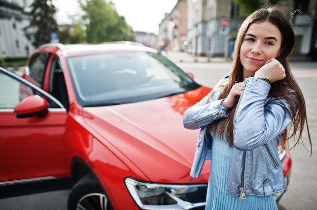 Retrato al aire libre de hermosa mujer posando junto a suv naranja