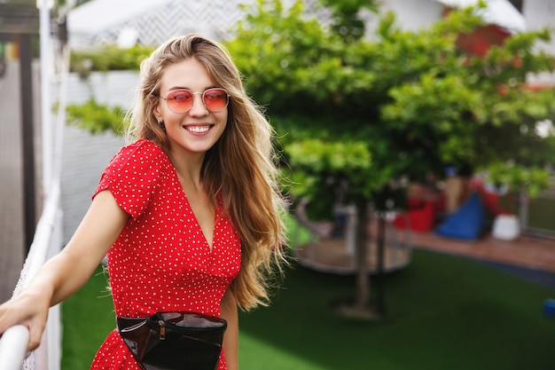 Retrato al aire libre de hermosa mujer rubia divirtiéndose en las calles de la ciudad de pie en un parque.