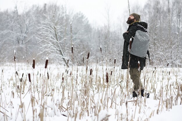 Retrato al aire libre de hombre guapo en abrigo y caspa. Hombre barbudo en el bosque de invierno.