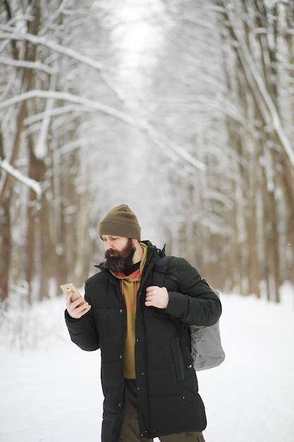 Retrato al aire libre de hombre guapo en abrigo y caspa. Hombre barbudo en el bosque de invierno.