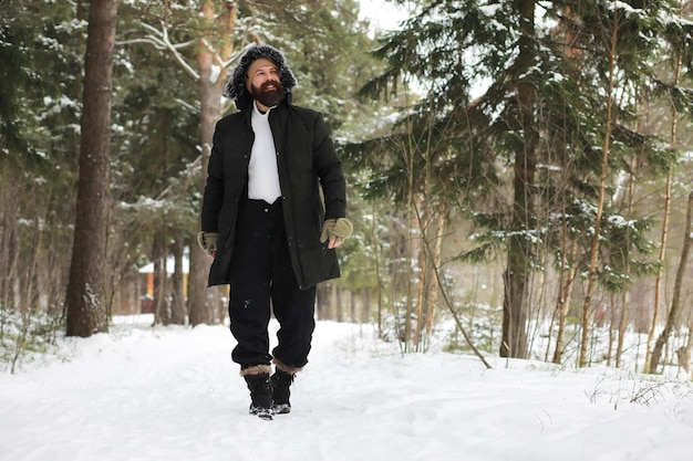 Retrato al aire libre de hombre guapo en abrigo y caspa. Hombre barbudo en el bosque de invierno.