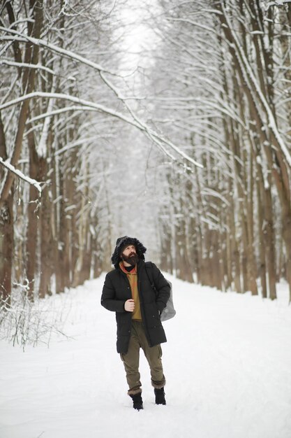 Retrato al aire libre de hombre guapo en abrigo y caspa. Hombre barbudo en el bosque de invierno.