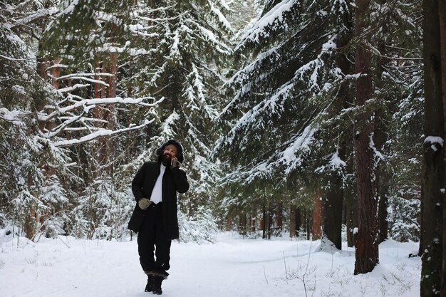 Retrato al aire libre de hombre guapo en abrigo y caspa. Hombre barbudo en el bosque de invierno.