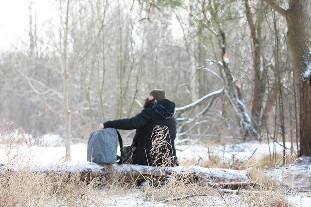 Retrato al aire libre de hombre guapo en abrigo y caspa. Hombre barbudo en el bosque de invierno.