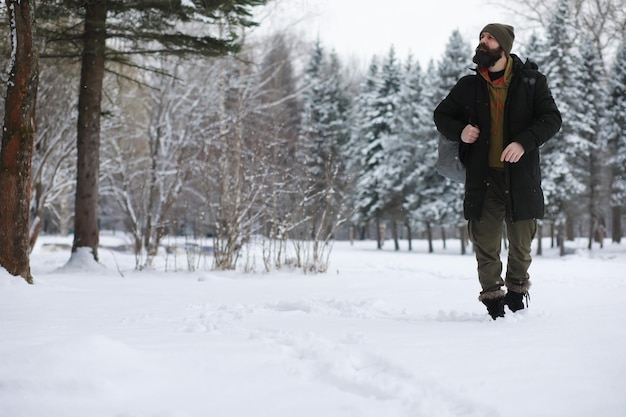 Retrato al aire libre de hombre guapo en abrigo y caspa. Hombre barbudo en el bosque de invierno.