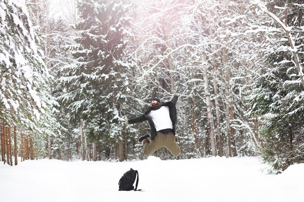 Retrato al aire libre de hombre guapo en abrigo y caspa. Hombre barbudo en el bosque de invierno.