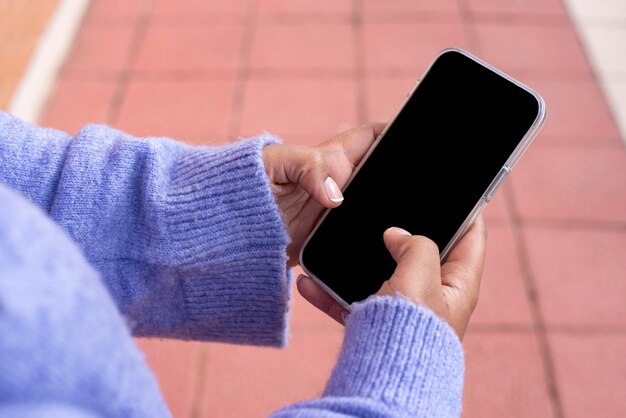 Retrato al aire libre de una joven afroamericana negra enviando mensajes de texto por teléfono móvil