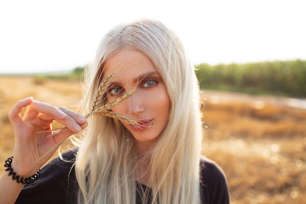 Retrato al aire libre de la joven belleza rubia con espigas de trigo en las manos.