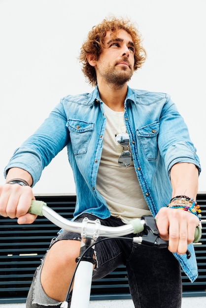 Retrato al aire libre de joven guapo con bicicleta de piñón fijo en la calle.