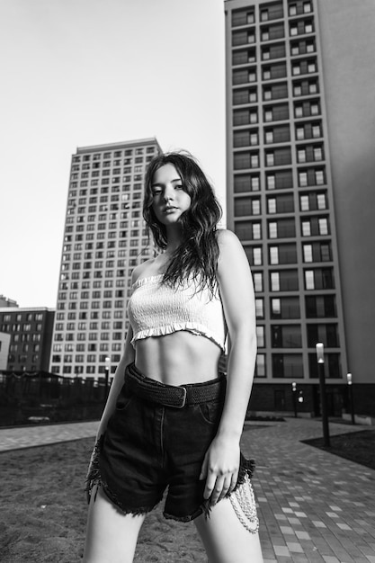 Retrato al aire libre de una joven hermosa mujer en pantalones cortos y top posando contra el fondo de la ciudad