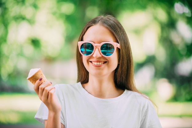 Retrato al aire libre joven inconformista loca niña comiendo helado clima del verano espejo redondo gafas de sol