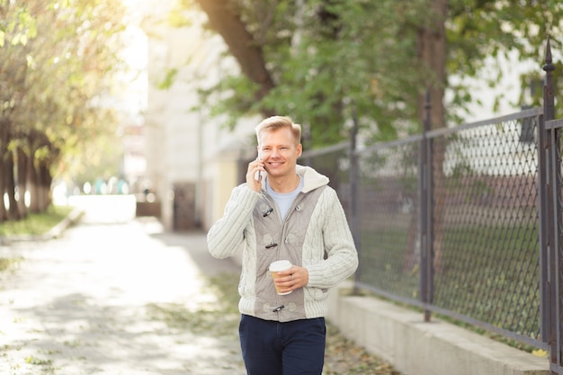 Retrato al aire libre del joven moderno hablando con teléfono móvil en las calles de la ciudad