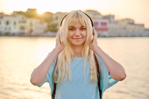 Retrato al aire libre de una joven rubia feliz con auriculares