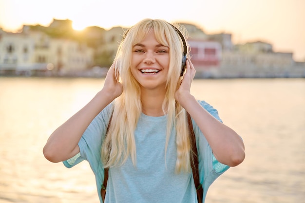 Retrato al aire libre de una joven rubia feliz con auriculares