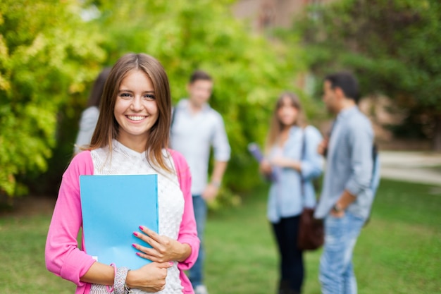 Retrato al aire libre de una joven sonriente frente a un grupo de estudiantes