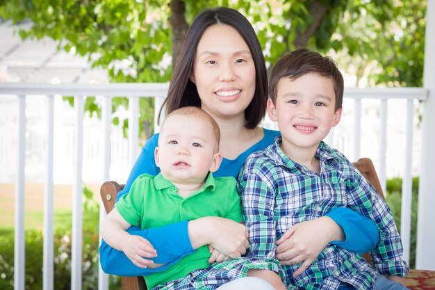 Retrato al aire libre de una madre china con sus dos niños chinos y caucásicos de raza mixta
