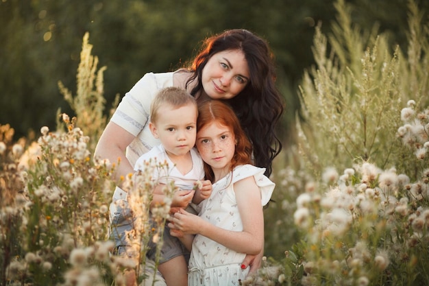 Retrato al aire libre de una madre sonriente que ama abrazar a dos hijos, hijo e hija