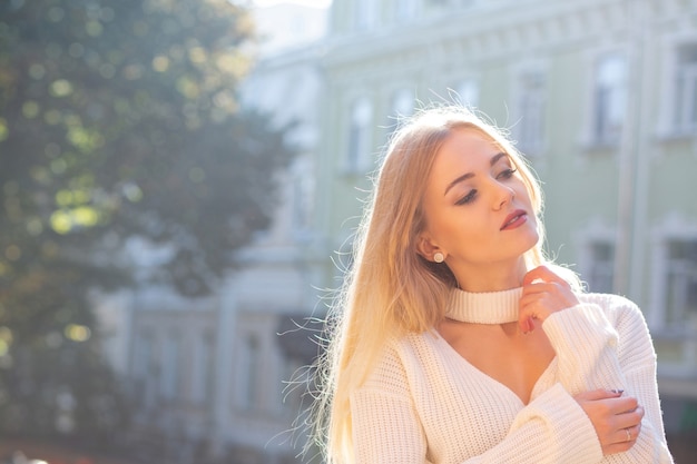 Retrato al aire libre de magnífica modelo con elegante traje posando en la calle con luz natural del sol. Espacio vacio