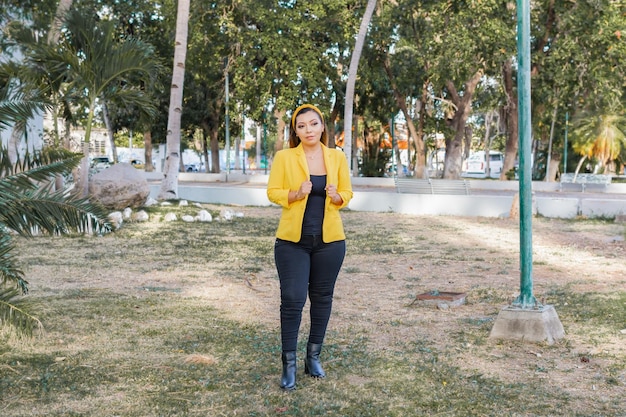 Retrato al aire libre de mujer con chaqueta amarilla Retrato de joven mexicana en un jardín al atardecer