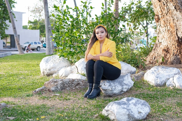 Retrato al aire libre de mujer con chaqueta amarilla Retrato de joven mexicana en un jardín al atardecer