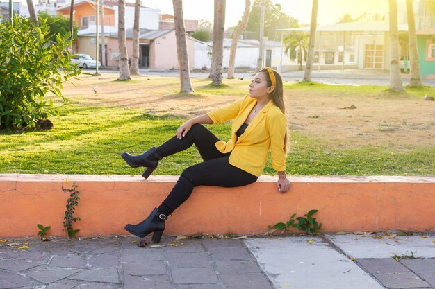 Retrato al aire libre de mujer con chaqueta amarilla Retrato de joven mexicana en un jardín al atardecer