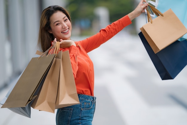 Retrato al aire libre de mujer feliz con bolsas de compras y cara sonriente en el centro comercial