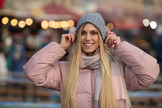 Retrato al aire libre de la mujer feliz en fondo del bokeh de la luz de la Navidad.