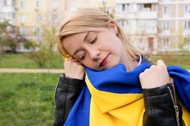 Retrato al aire libre de una mujer joven con la bandera de Ucrania en la calle de la ciudad El concepto de libertad