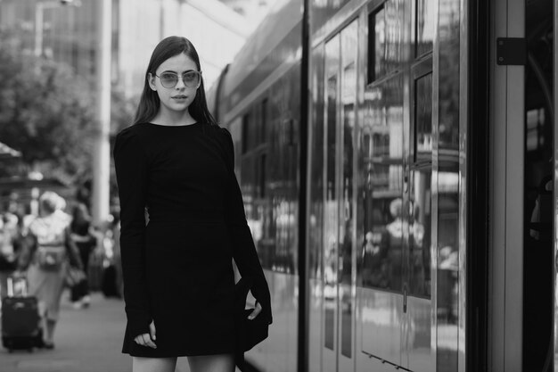 Retrato al aire libre de una mujer joven y elegante que espera un trolebús, un modelo de moda joven de estilo urbano